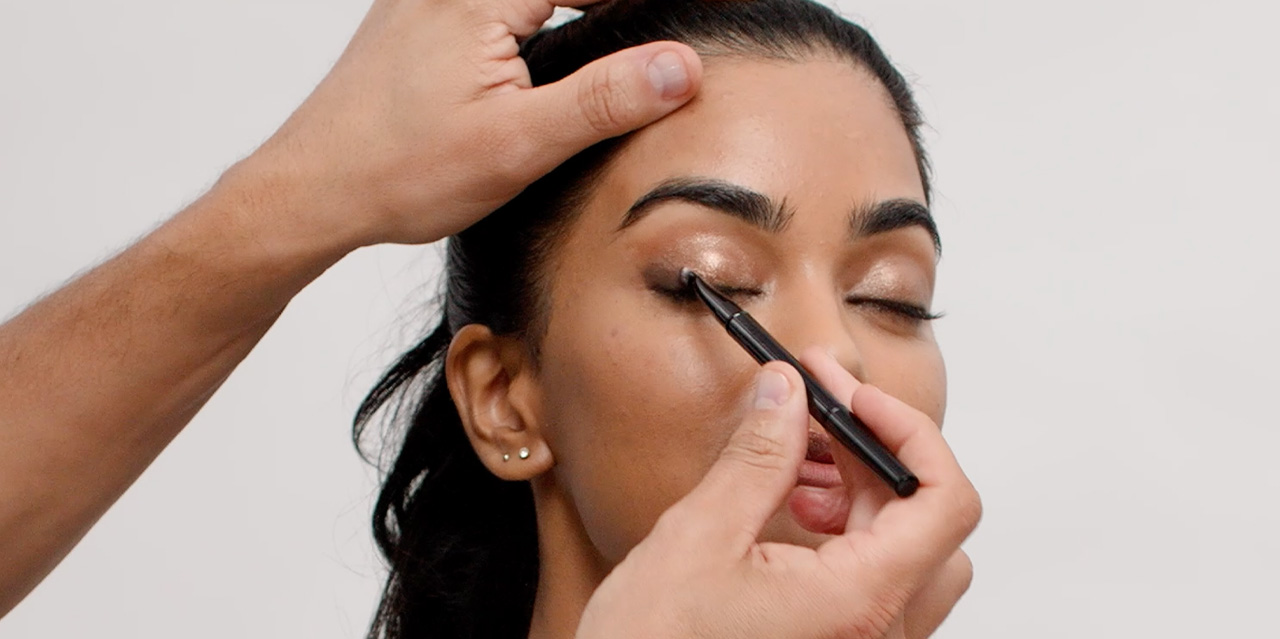 Makeup artists applying a deep chocolate eyeshadow shade as eyeliner